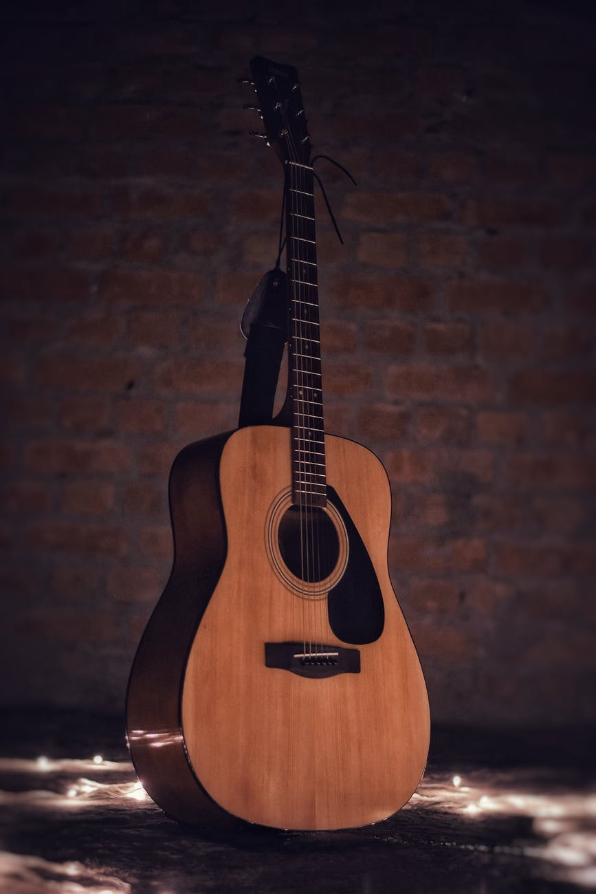 acoustic guitar on brown brick wall